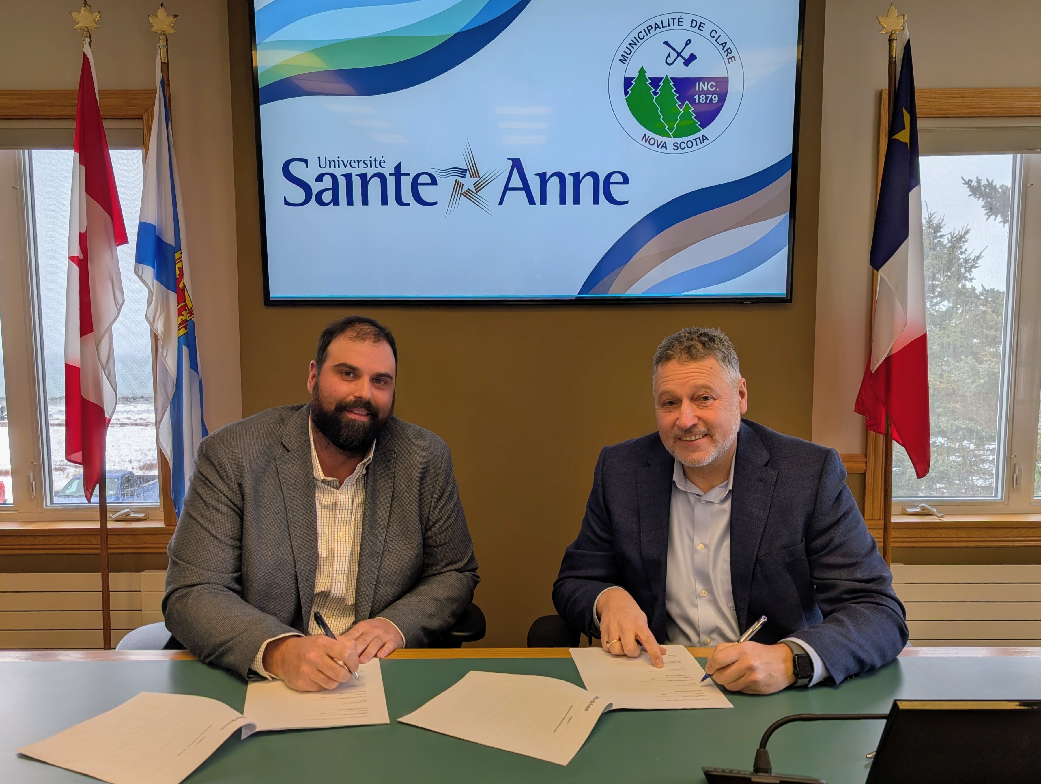 Une photo du préfet Yvon LeBlanc et du recteur et vice-chancelier Kenneth Deveau signant l'accord.